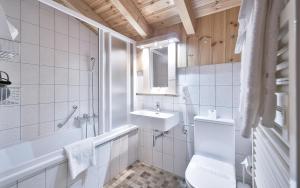 a bathroom with a sink and a toilet and a tub at Hôtel Le Chamois in Les Diablerets +39 photos