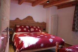 a bedroom with a bed with a red blanket with snowflakes at CAV MES VALLEES La Thuile in La Thuile