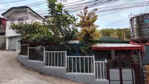 a building with a fence and trees in front of it at Kochimoto Guestroom in Baguio