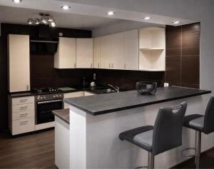 a kitchen with white cabinets and a counter with stools at Oaza Resnik in Zagreb