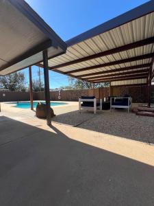 a patio with two benches under awning next to a pool at Midland Luxe, Pool, Fire Pit, Workspace, Pool Table in Midland