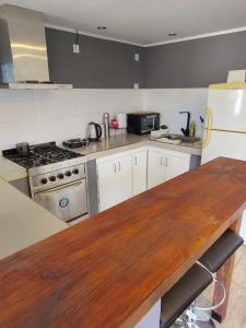a kitchen with a wooden counter top and a refrigerator at Quincho Monoambiente Con Parrilla in Balcarce