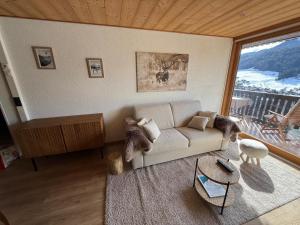 a living room with a couch and a large window at Morz'Inn Vue panoramique sur les montagnes in Morzine