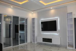 a living room with a television on a wall at MB Properties - situated behind Dalaba Estate about 500 meters from the famous OIC road in Madina Sey Kunda