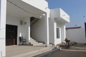a white house with stairs and a door at MB Properties - situated behind Dalaba Estate about 500 meters from the famous OIC road in Madina Sey Kunda