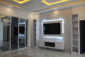 a living room with a television on a wall at MB Properties - situated behind Dalaba Estate about 500 meters from the famous OIC road in Madina Sey Kunda