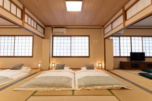 a large room with three beds in it with windows at 大吉屋2号館 ワンフロア貸切部屋 名駅離れ in Nagoya