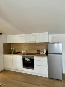 a kitchen with white cabinets and a refrigerator at Apartman Lukas in Županja