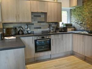 a kitchen with wooden cabinets and a stove top oven at Rosecraddoc Manor - Stable in Saint Cleer