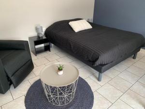 a bedroom with a bed and a table and a couch at studio meublé, résidence calme in Saint-Amand-les-Eaux