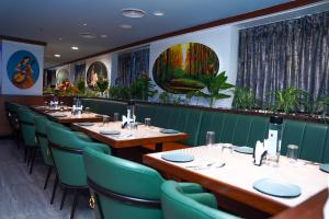 a restaurant with wooden tables and green chairs at Hotel Sarovaras Legacy in Bangalore