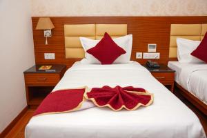 a hotel room with two beds with red pillows at Hotel Sarovaras Legacy in Bangalore