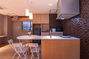 a kitchen with a kitchen island with chairs and a counter top at Kawasaki Central House in Kawasaki