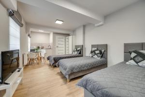 a bedroom with two beds and a kitchen with a table at Central Platinum Apartments 18 Studio z aneksem kuchennym i tarasem - 3 łóżka in Rybnik