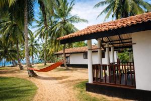 a house with a hammock in front of a building at Helios Beach Resort in Tangalle