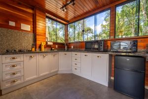 a kitchen with white cabinets and a large window at Recanto do Bici in Urubici