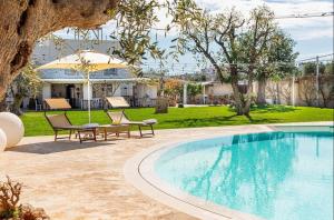 a swimming pool in a yard with two chairs and a house at Masseria Ancella in Montalbano