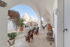 an archway with benches and potted plants on a courtyard at Masseria Ancella in Montalbano