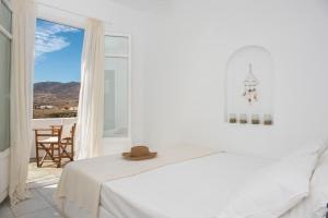 a white bedroom with a bed and a large window at Cleopatra Seaside Homes in Piso Livadi