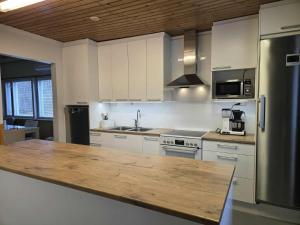 a kitchen with white cabinets and a wooden counter top at Leinosen Lempi in Ylämylly +13 photos