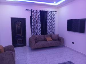 a living room with a couch and a flat screen tv at Perry Hills Apartment in Tokuse