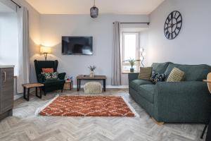 a living room with a green couch and two chairs at Bignold Park View in Orkney