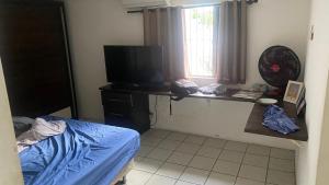 a room with a bed and a desk with a television at Casa Carnaval Olinda 2026 in Recife