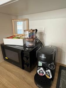 a coffee maker and a blender on top of a microwave at La Douce Escale studio in Courseulles-sur-Mer