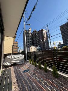 a fence in front of a city with tall buildings at 青梅森の宿3号館新築一棟貸し東青梅駅徒歩3分最大11人 in Ome