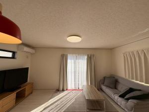 a living room with a couch and a large window at 青梅森の宿3号館新築一棟貸し東青梅駅徒歩3分最大11人 in Ome