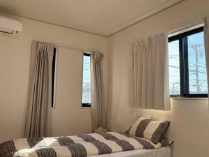 a bedroom with a bed and two windows at 青梅森の宿3号館新築一棟貸し東青梅駅徒歩3分最大11人 in Ome