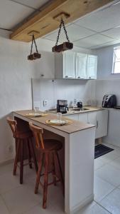 a kitchen with a counter with two chairs and a island at Refúgio da Lagoa de Araruama - AP 202 in Araruama