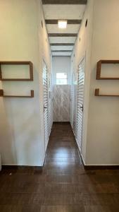 a hallway with white walls and wooden floors and shutters at Complexo Luquinha in Delfinópolis
