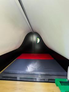 a bed in a small room with a red and blue mattress at Ermida Gerês Camping in Ermida