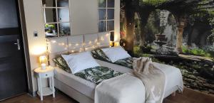 a bedroom with a bed with a picture on the wall at Apartamenty dla par Stara Szkoła in Weremowice