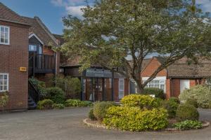 a brick building with a tree in front of it at Kings Court Hotel Alcester, BW Signature Collection in Stratford-upon-Avon