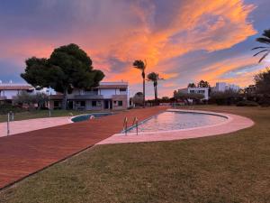 a swimming pool in a park with a sunset at Les Oliveres Beach in Perelló