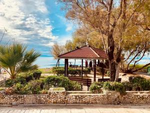 a gazebo in a park with a bench and trees at Cozy Studio by seaside and tram in Athens