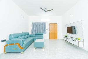a living room with a blue couch and a tv at Aikya Service Apartment in Hyderabad
