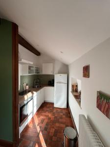 a kitchen with a white refrigerator and a brick floor at Loft Blois Cathédrale 2 Chambres in Blois