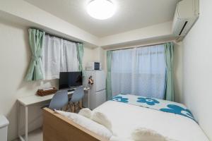 a bedroom with a bed and a desk and a television at Mary's Room Hakata in Sumiyoshi