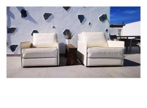 two white chairs sitting next to each other in front of a wall at Villa Gozo Holiday house in Teguitar