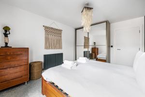 a bedroom with a large bed and a dresser at Stylish Flat next2 Wimbledon with a parking in Mitcham Junction