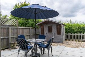 a patio with a table and chairs and an umbrella at 2 Bedroom Rural Escape In Peaceful Elmswell in Woolpit