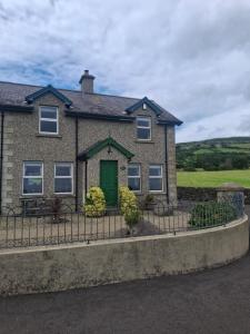 a house with a green door and a fence at Redbrae cottage in Carnlough