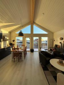 a kitchen and living room with a table and chairs at Modern waterfront rorbu with terrace and stunning sea view - free parking in Stamsund
