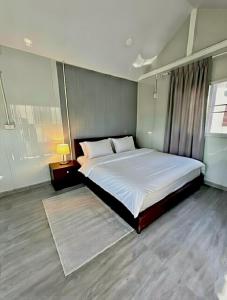a bedroom with a large white bed and a lamp at Baan Pranai In Pai in Pai