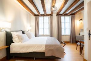 a bedroom with a large bed and two windows at L'Hostellerie de La Licorne in Fontevraud-l'Abbaye