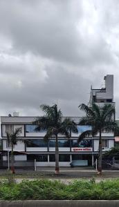 a building with palm trees in front of it at Sukhawan Hotel in Kalamb