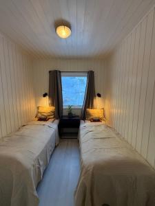 two beds in a room with a window at Modern waterfront rorbu with terrace and stunning sea view - free parking in Stamsund